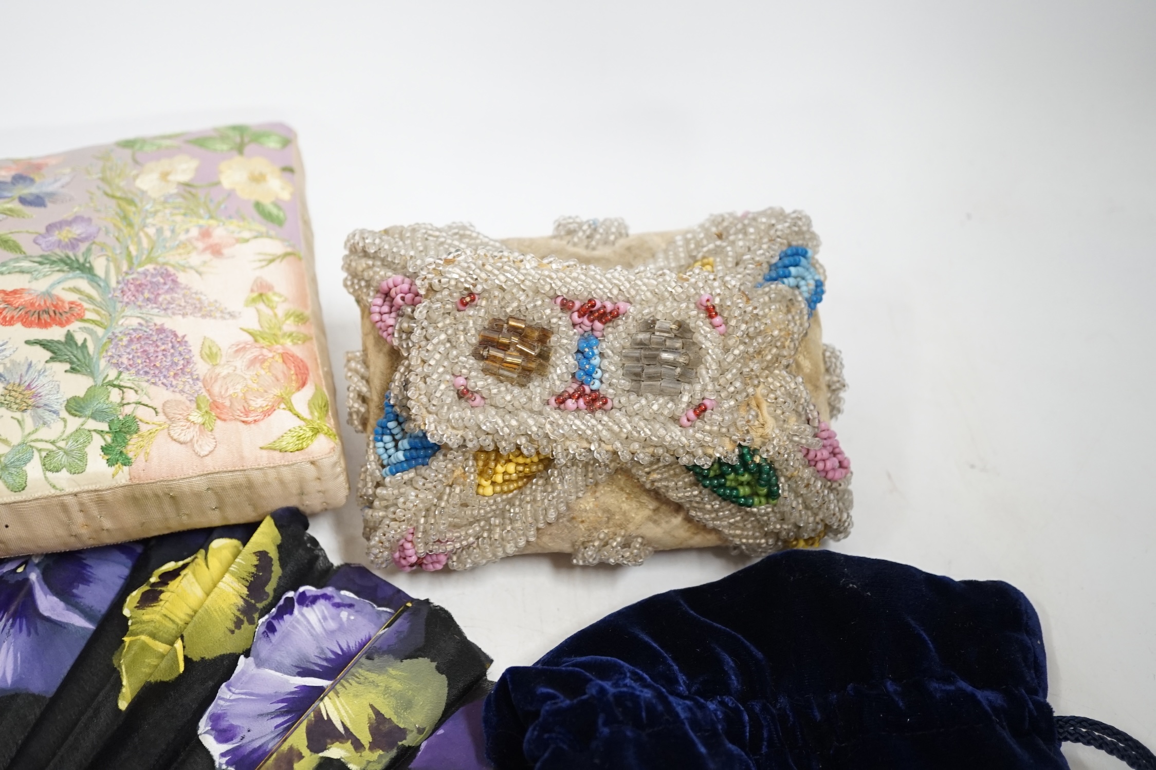 A Chinese 1920’s boxed carved bone and silk embroidered dragon fan, a larger European pansy decorated fan, a bead worked basket, a mat, two cut steel necklaces, an embroidered pin cushion, an evening bag and a misers pur